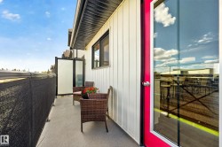 Exterior balcony featuring a concrete surface, black privacy screening, and a frosted glass partition - 