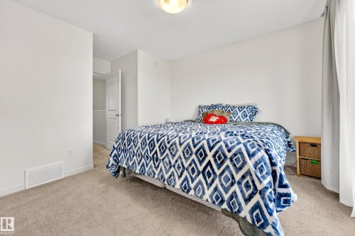 Bedroom featuring light neutral wall paint, textured ceiling, carpeting, white trim, and a white interior door - 38 Jensen Gate, St. Albert, AB - Indoor Photo Showing Bedroom