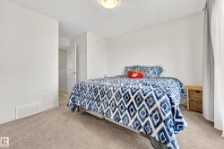 Bedroom featuring light neutral wall paint, textured ceiling, carpeting, white trim, and a white interior door - 