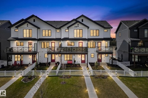 Modern farmhouse-style townhome exteriors featuring white siding, black trim accents, and prominent gables - 38 Jensen Gate, St. Albert, AB - Outdoor With Balcony With Facade