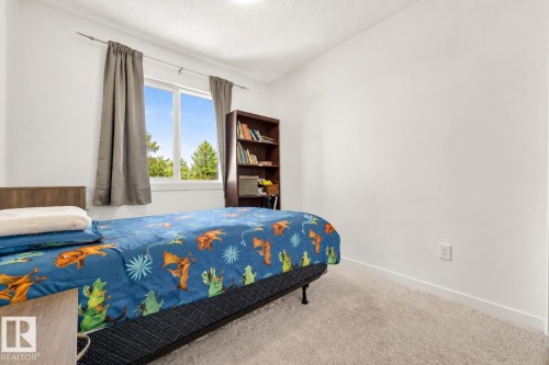 Bedroom featuring a large window, light-colored carpeting, white walls, and a built-in bookshelf - 38 Jensen Gate, St. Albert, AB - Indoor Photo Showing Bedroom
