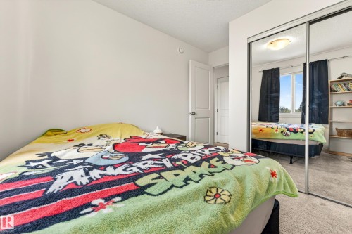 Bedroom featuring neutral wall paint, carpet flooring, a white interior door, a mirrored closet, and a ceiling-mounted light fixture - 38 Jensen Gate, St. Albert, AB - Indoor Photo Showing Bedroom