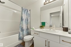 Full bathroom featuring a white tub-shower combination, a toilet, a vanity with an integrated sink, and wood-finish flooring - 
