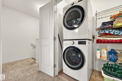 Dedicated laundry area featuring a stackable washer and dryer, adjacent to white paneled doors and neutral carpeting - 