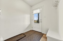 Entryway featuring a white paneled door with glass inserts, transom window, and a built-in white bench - 
