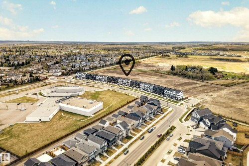 Aerial perspective showcasing a developing community with established residential areas, new construction townhomes, and single-family residences - 38 Jensen Gate, St. Albert, AB - Outdoor With View
