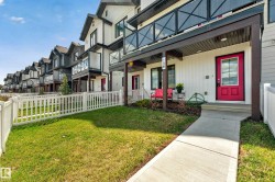 Contemporary townhome exterior featuring white vertical siding, a bright red entry door, and a private balcony with glass railing - 