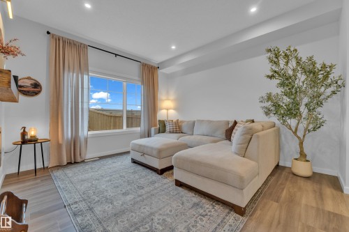 Bright living area featuring large windows with outdoor scenery, recessed lighting, and wood-finish flooring - 17319 2 St Nw, Edmonton, AB - Indoor Photo Showing Living Room