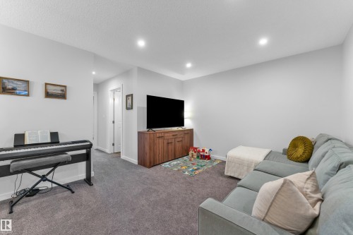 Recessed lighting illuminates this carpeted room, featuring a built-in media console with wood-finish cabinetry - 17319 2 St Nw, Edmonton, AB - Indoor