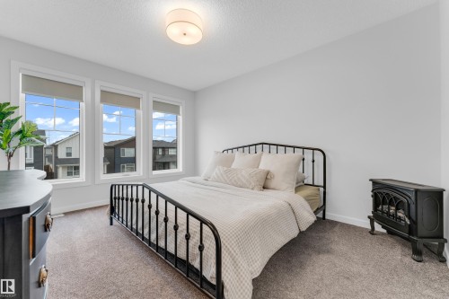 Bright room featuring three large windows with roller shades, neutral carpeting, and a flush mount ceiling light fixture - 17319 2 St Nw, Edmonton, AB - Indoor Photo Showing Bedroom