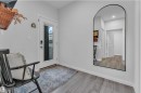 Entryway featuring light gray walls, wood-finish flooring, and a contemporary arched mirror - 17319 2 St Nw, Edmonton, AB  - Indoor Photo Showing Other Room 