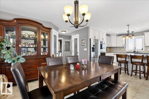 The dining area features tiled flooring, an elegant chandelier, and a pantry door with a frosted glass panel - 531064 Range Road 174, Rural Lamont County, AB - Indoor Photo Showing Dining Room
