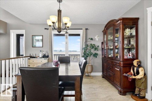 The bathroom features a vanity with a white countertop and a single sink, light-colored square floor tiles, and a shower-tub combination with a patterned shower curtain - 531064 Range Road 174, Rural Lamont County, AB - Indoor Photo Showing Bathroom