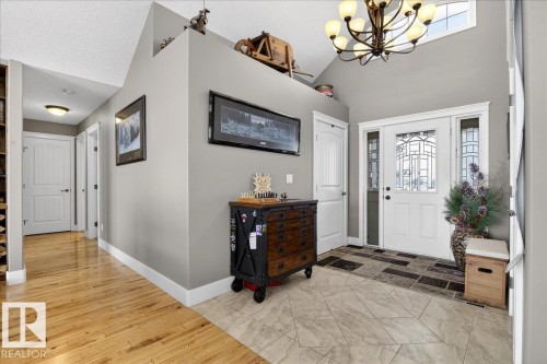 Inviting entryway featuring a white paneled front door with decorative glass inserts, a vaulted ceiling, and a chandelier - 531064 Range Road 174, Rural Lamont County, AB - Indoor Photo Showing Other Room