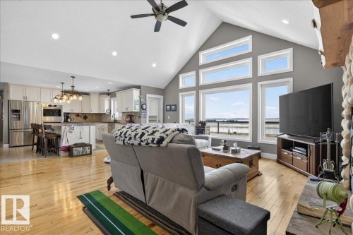 The living area features a vaulted ceiling, a stone fireplace, and large windows - 531064 Range Road 174, Rural Lamont County, AB - Indoor Photo Showing Living Room With Fireplace