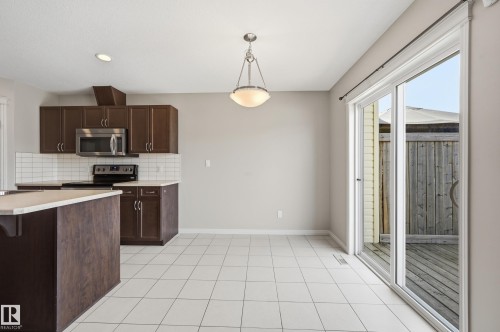 Kitchen featuring dark wood-finish cabinetry, stainless steel microwave, and white subway tile backsplash - 2170 52A Street Sw, Edmonton, AB - Indoor Photo Showing Kitchen With Stainless Steel Kitchen