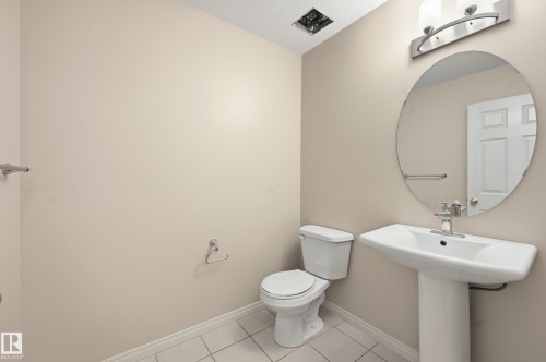 Pedestal sink with chrome faucet, complemented by an oval mirror and contemporary vanity lighting - 2170 52A Street Sw, Edmonton, AB - Indoor Photo Showing Bathroom