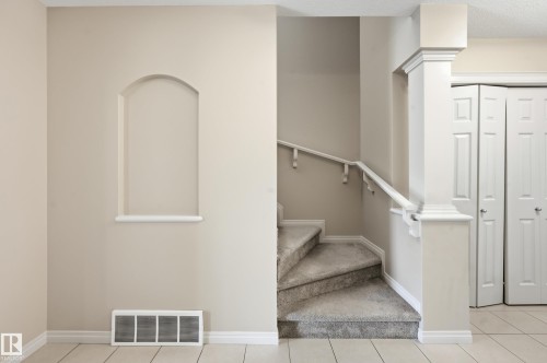 Carpeted staircase featuring a white handrail and a decorative architectural column - 2170 52A Street Sw, Edmonton, AB - Indoor Photo Showing Other Room