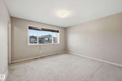 Neutral-toned room featuring light gray carpeting and a wide window with horizontal blinds - 2170 52A Street Sw, Edmonton, AB - Indoor Photo Showing Other Room