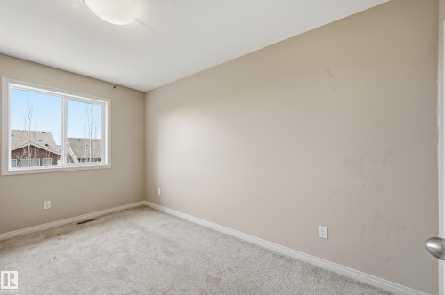 Neutral-toned room featuring a white-framed window, light gray carpet, and white baseboards - 2170 52A Street Sw, Edmonton, AB - Indoor Photo Showing Other Room