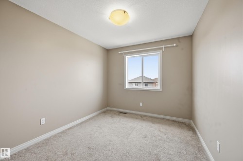 Bedroom featuring neutral-toned walls, light-colored carpet, a double-paned window, and a flush-mount ceiling light - 2170 52A Street Sw, Edmonton, AB - Indoor Photo Showing Other Room