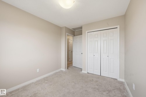 Neutral tone walls, light gray carpeting, bi-fold closet doors, white baseboards, and a semi-flush mount ceiling light fixture - 2170 52A Street Sw, Edmonton, AB - Indoor