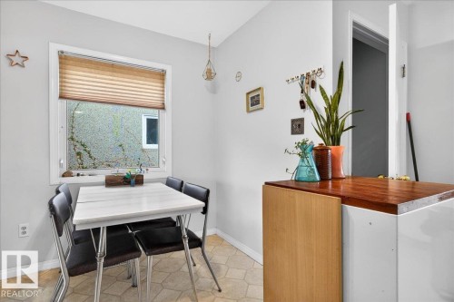 Windowed dining area featuring a light-toned table, neutral wall paint, and geometric floor tiling - 4212 105 Avenue, Edmonton, AB - Indoor Photo Showing Dining Room