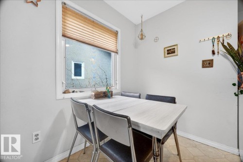 Compact dining area featuring a window with blinds, neutral wall paint, and geometric tile flooring - 4212 105 Avenue, Edmonton, AB - Indoor Photo Showing Dining Room