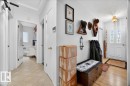 Entryway featuring a decorative front door with arched glass inserts, light wood-finish flooring, white trim, and a hallway leading to an interior room with a window and vanity - 4212 105 Avenue, Edmonton, AB  - Indoor Photo Showing Other Room 