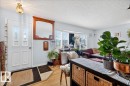 Entryway featuring a white paneled door with decorative glass inserts, wood-finish flooring, a wall-mounted light fixture, and a large bay window - 4212 105 Avenue, Edmonton, AB  - Indoor 