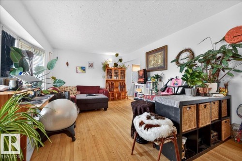 Spacious living area featuring wood-finish flooring, white walls, and a large window with horizontal blinds - 4212 105 Avenue, Edmonton, AB - Indoor Photo Showing Living Room