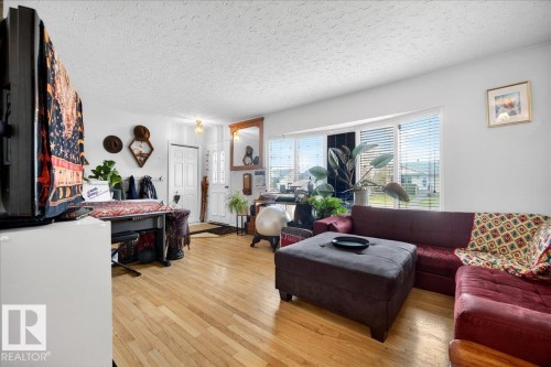 Living area featuring wood-finish flooring and a multi-pane bay window - 4212 105 Avenue, Edmonton, AB - Indoor Photo Showing Living Room