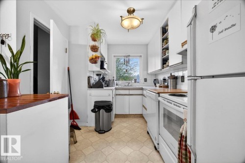 Bright kitchen featuring white cabinetry and appliances, wood-finish countertops, and a patterned floor - 4212 105 Avenue, Edmonton, AB - Indoor Photo Showing Kitchen