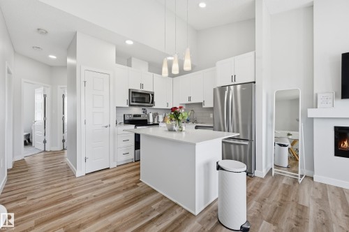 Open-concept kitchen featuring white cabinetry, stainless steel appliances, a central island with a solid surface countertop, and recessed lighting - 34 2905 141 Street, Edmonton, AB - Indoor Photo Showing Kitchen With Upgraded Kitchen