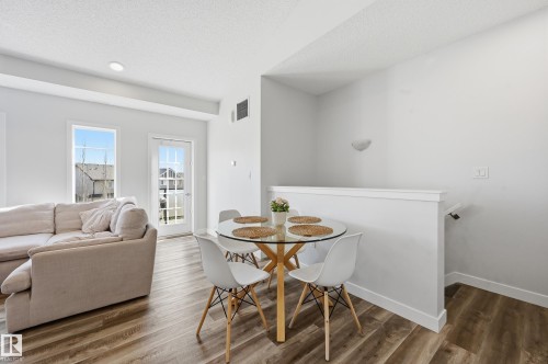 Open-concept living space featuring wood-finish flooring, recessed lighting, and a white painted railing - 34 2905 141 Street, Edmonton, AB - Indoor