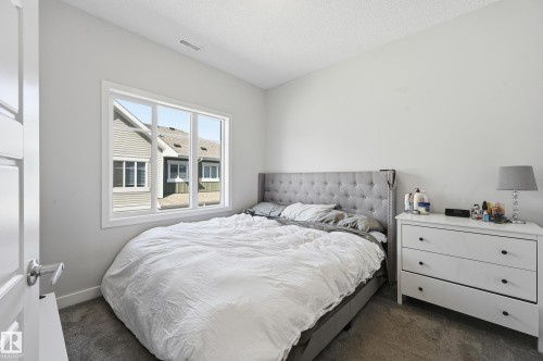 Bedroom featuring a multi-pane window, light-toned walls, and grey carpet flooring - 34 2905 141 Street, Edmonton, AB - Indoor Photo Showing Bedroom