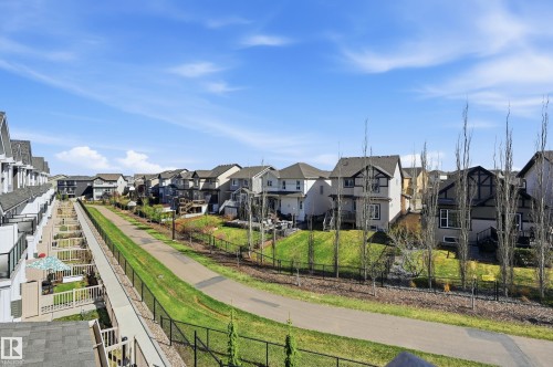 Residential street featuring a paved pathway, manicured green space, and varied home exteriors - 34 2905 141 Street, Edmonton, AB - Outdoor With Facade