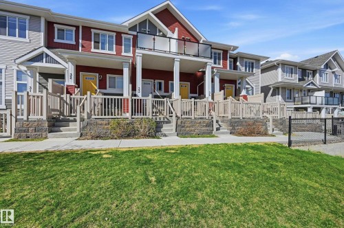 Townhome exterior featuring red and gray siding, white trim, and individual front porches with railings - 34 2905 141 Street, Edmonton, AB - Outdoor With Facade