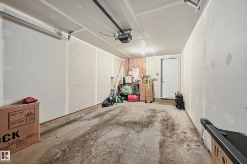 Garage with an automatic opener, exposed ceiling joists, and an interior access door - 34 2905 141 Street, Edmonton, AB - Indoor Photo Showing Garage