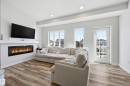 Living area showcasing a contemporary linear fireplace with a white mantel, wood-finish flooring, recessed lighting, and a glass-paneled exterior door - 34 2905 141 Street, Edmonton, AB  - Indoor Photo Showing Living Room With Fireplace 