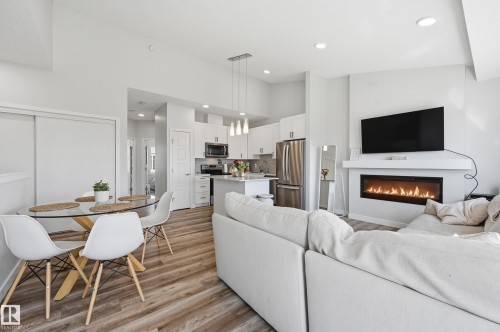 Open-concept living area featuring wood-finish flooring, a contemporary linear fireplace with a mantel, and recessed ceiling lighting - 34 2905 141 Street, Edmonton, AB - Indoor With Fireplace