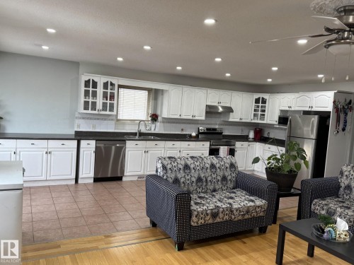 Spacious kitchen featuring white cabinetry, dark countertops, and stainless steel appliances - 3139 34B Avenue, Edmonton, AB 