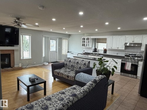 Open-concept living area featuring a kitchen with white cabinetry and stainless steel appliances - 3139 34B Avenue, Edmonton, AB - Indoor Photo Showing Living Room With Fireplace