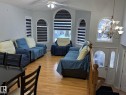 Living area featuring hardwood flooring, arched windows with horizontal blinds, a ceiling fan, and a multi-tiered chandelier - 3139 34B Avenue, Edmonton, AB 