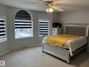 Carpeted room featuring an arched window, two additional rectangular windows, and a ceiling fan with integrated lighting - 3139 34B Avenue, Edmonton, AB 