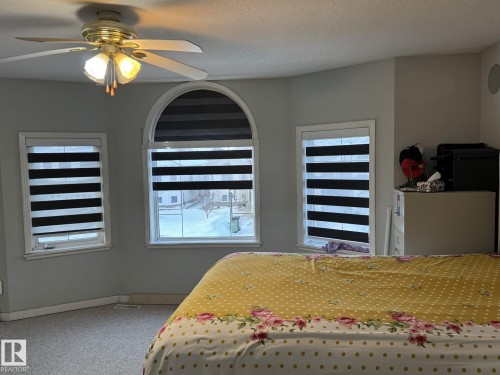 Triple window ensemble featuring an arched central window and two rectangular side windows, each fitted with horizontal striped blinds - 3139 34B Avenue, Edmonton, AB 