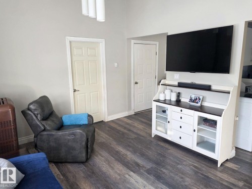 Spacious living area featuring wood-finish flooring, light gray walls, and recessed lighting. - 4825 52 Street, Elk Point, AB - Indoor