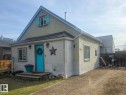 Light-colored stucco exterior with a contrasting teal entry door and shutters. - 4825 52 Street, Elk Point, AB  - Outdoor With Deck Patio Veranda 