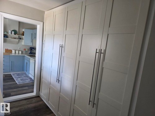 Integrated white paneled cabinetry with long black pulls. - 4825 52 Street, Elk Point, AB - Indoor Photo Showing Other Room