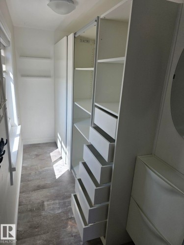 White built-in wardrobe system featuring open shelving and multiple storage drawers. - 4825 52 Street, Elk Point, AB - Indoor